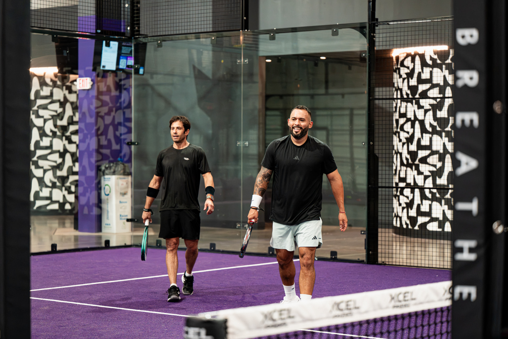 Two players walking off an indoor padel court