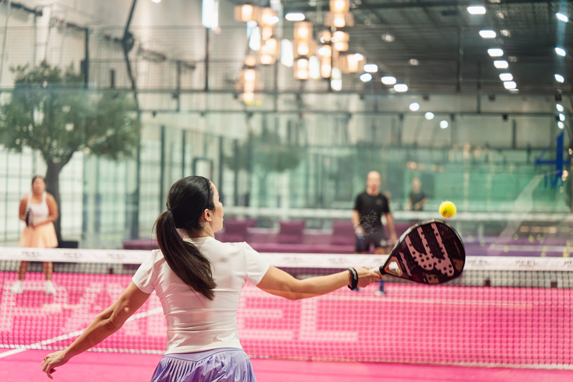 Player hitting a forehand on the pink padel court